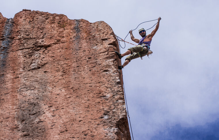 Climber hanging off the top of a rock