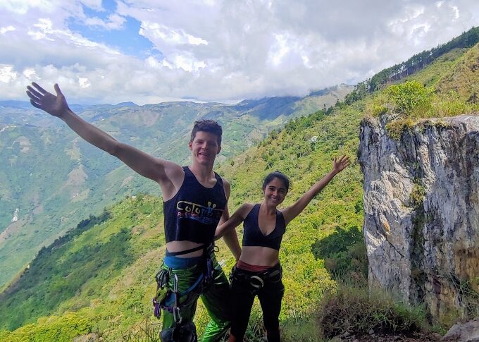 a young couple with their arms open in a welcome gesture on top of a high mountain in colombia