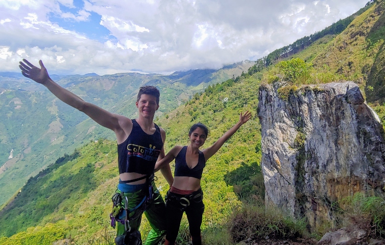 a young couple with their arms open in a welcome gesture on top of a high mountain in colombia